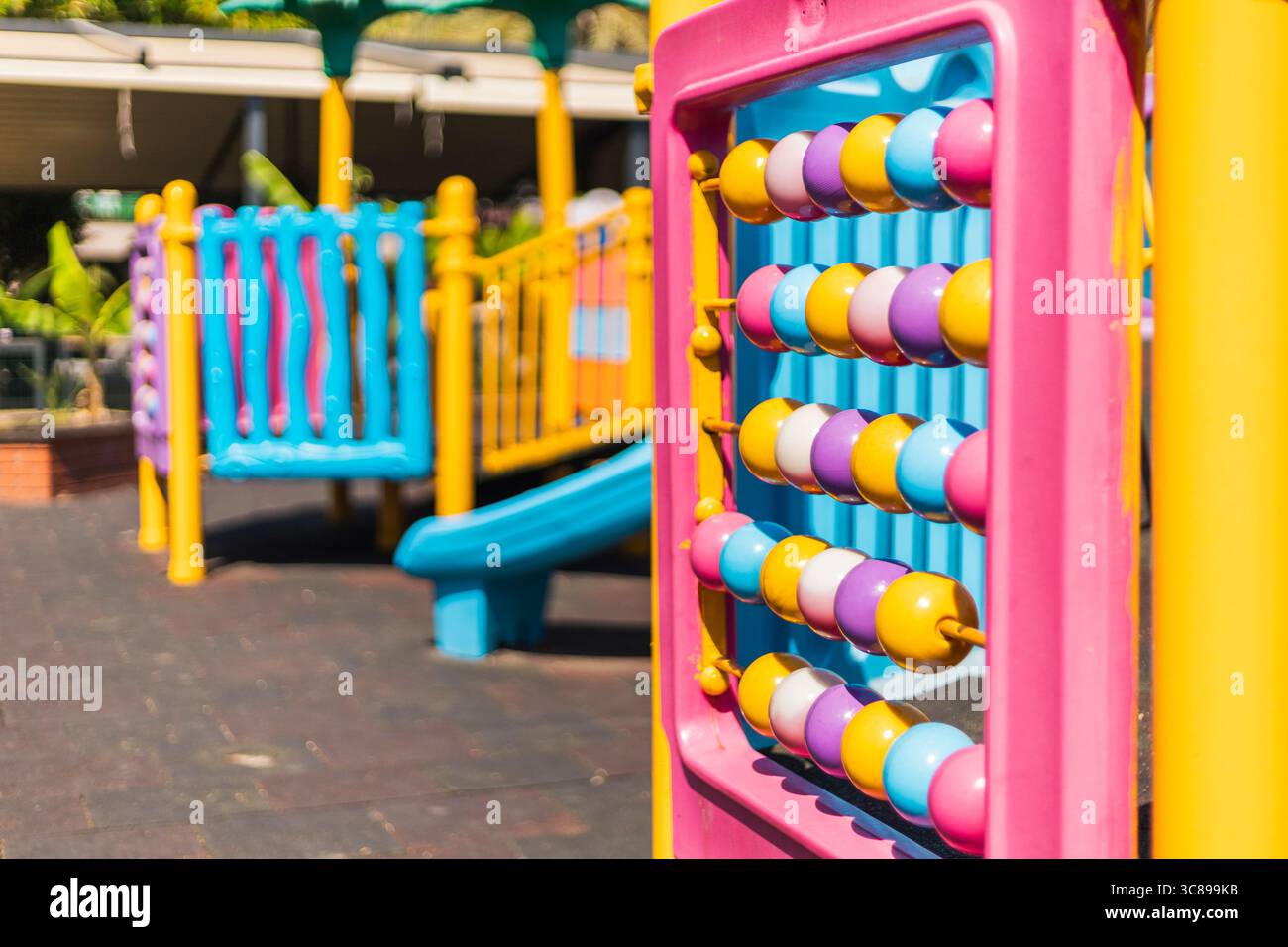 Die farbenfrohen Spielgeräte verfügen über einen rosafarbenen Abacus, Rutschen und Kletterstrukturen. Ideale Umgebung für Kinder, um kreativ zu spielen Stockfoto