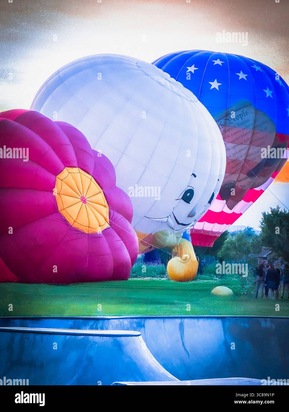 Sehen Sie, wie riesige Heißluftballons aus der Nähe am Boden in die Luft gehen und im Park bei einem lokalen Festival ausgestellt werden. Happy Face ist Humpty Dumpty auf 1 von 3. Stockfoto