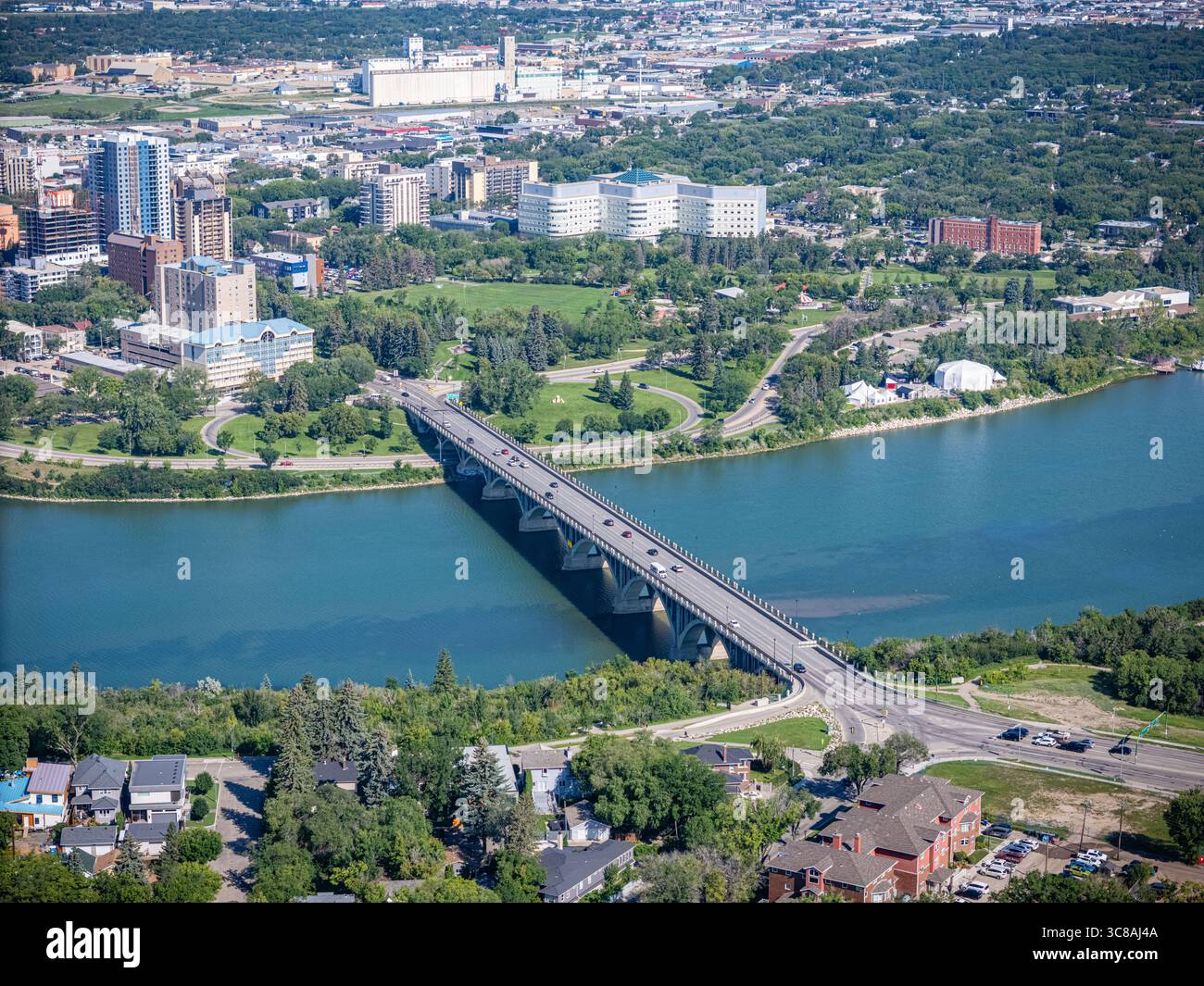 Blick auf die Stadt mit einer Brücke über einen Fluss. Die Brücke ist von Bäumen und Häusern umgeben. Die Stadt ist voller Aktivität und der Fluss ist ruhig und friedlich Stockfoto