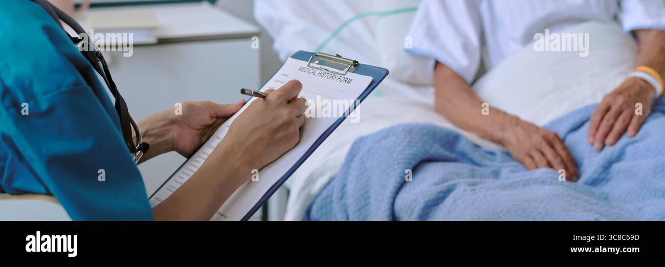Frau, die im Krankenhausbett liegt, während die Schwester Notizen macht Stockfoto