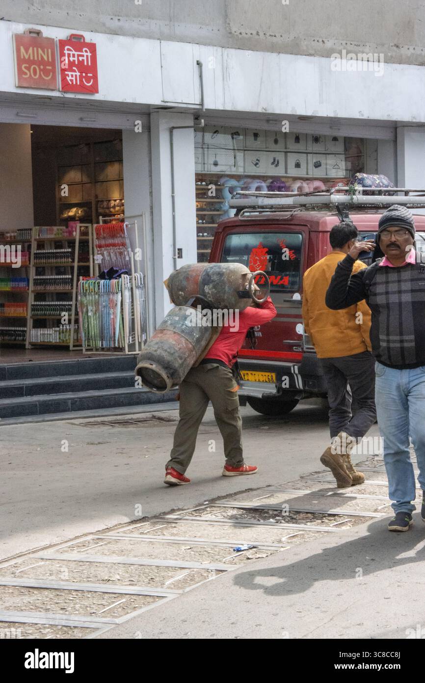 DARJEELING, WESTBENGALEN, INDIEN - 8. FEBRUAR 2024 typischer Mann mit zwei Treibgastanks auf dem Rücken den Hügel hinauf Stockfoto