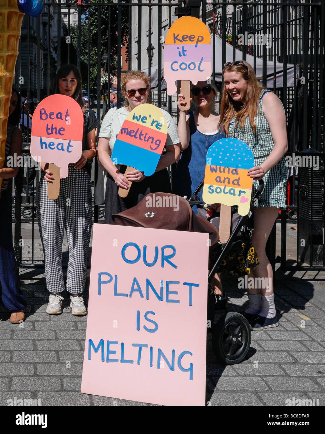 „Mothers Rise Up“-Klimaprotestantin vor der Downing Street mit einem großen, planetenförmigen Eiskegel, London, Großbritannien Stockfoto