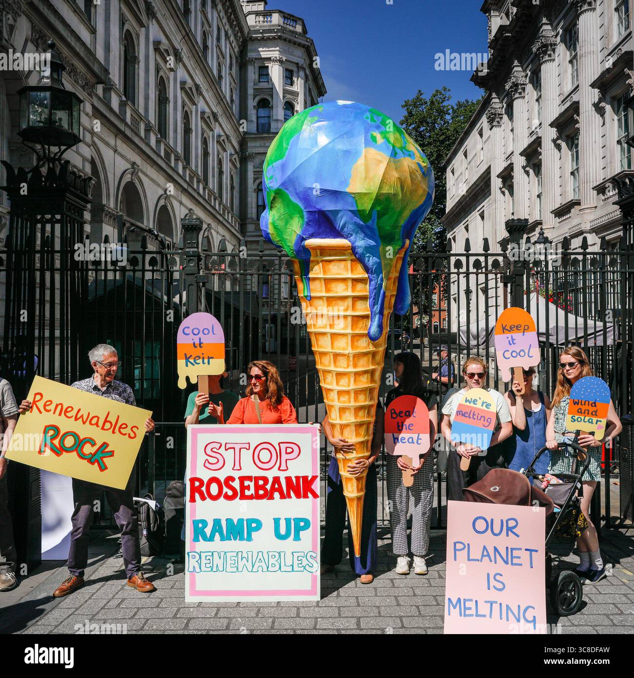 „Mothers Rise Up“-Klimaprotestantin vor der Downing Street mit einem großen, planetenförmigen Eiskegel, London, Großbritannien Stockfoto