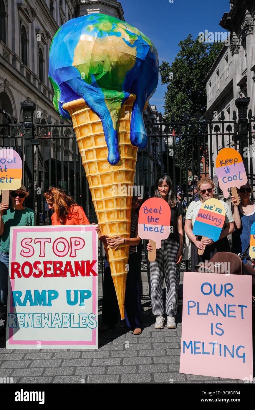 „Mothers Rise Up“-Klimaprotestantin vor der Downing Street mit einem großen, planetenförmigen Eiskegel, London, Großbritannien Stockfoto