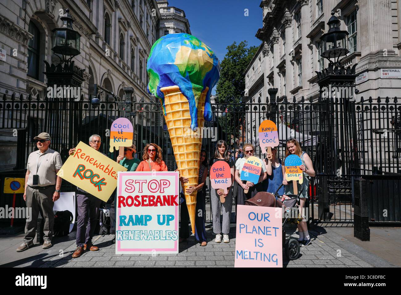 „Mothers Rise Up“-Klimaprotestantin vor der Downing Street mit einem großen, planetenförmigen Eiskegel, London, Großbritannien Stockfoto