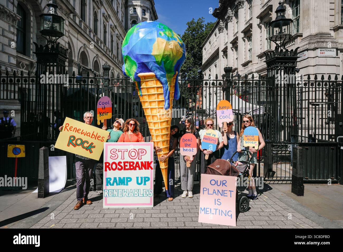 „Mothers Rise Up“-Klimaprotestantin vor der Downing Street mit einem großen, planetenförmigen Eiskegel, London, Großbritannien Stockfoto