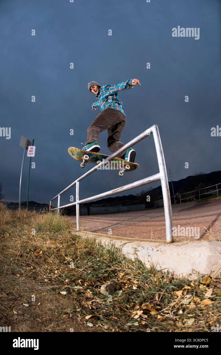 Ein Skateboarder, der an einem stürmischen Tag einen Trick am Handlauf macht. Stockfoto
