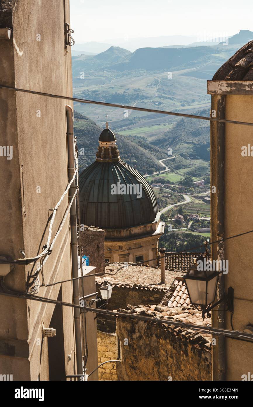 Barocke Kirchenkuppel in Gangi, Sizilien, eingerahmt von alten Gebäuden und Landschaft Stockfoto