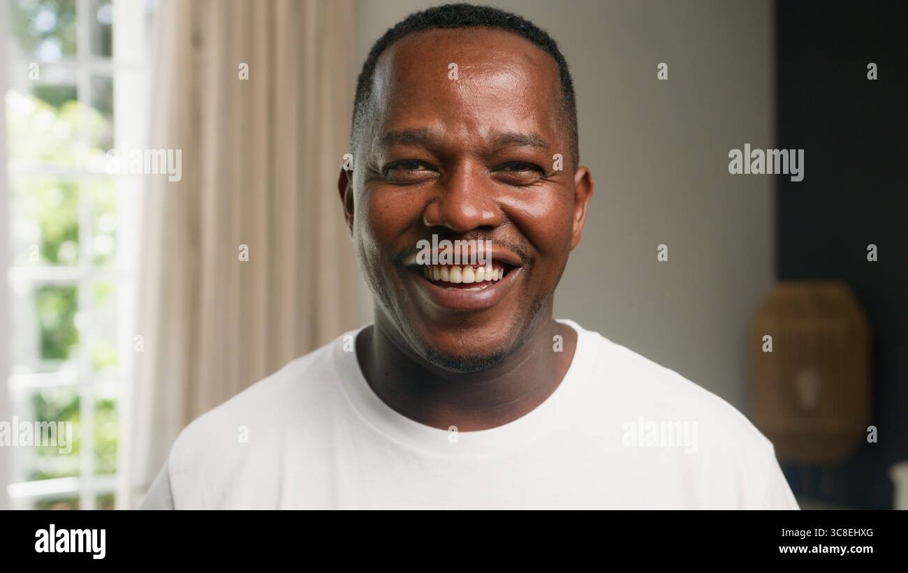 Fröhliches Porträt eines lächelnden Mannes in einer hellen Inneneinrichtung Stockfoto