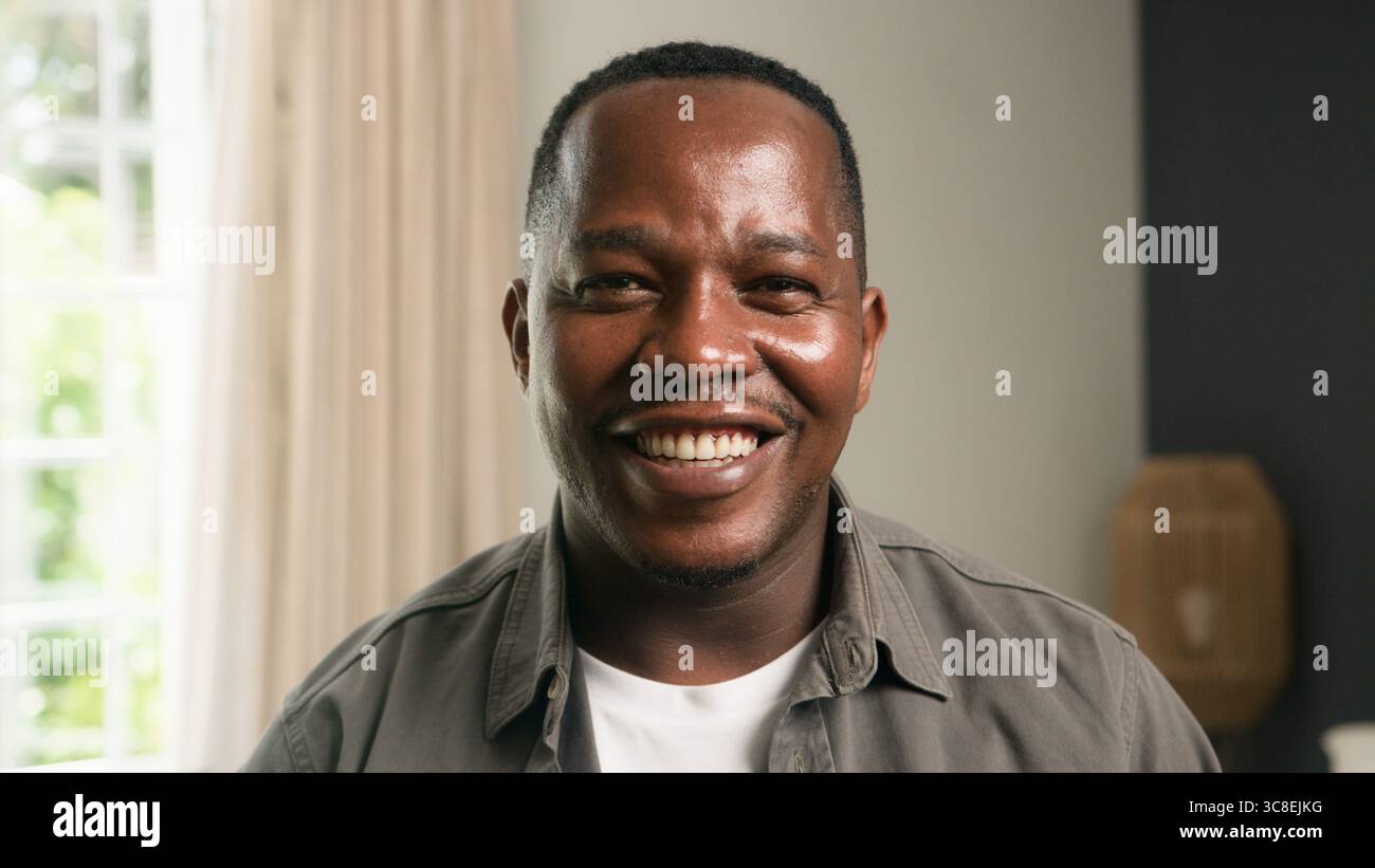 Lächelnde Person in einer hellen Wohnumgebung, die Wärme und Positivität zeigt Stockfoto