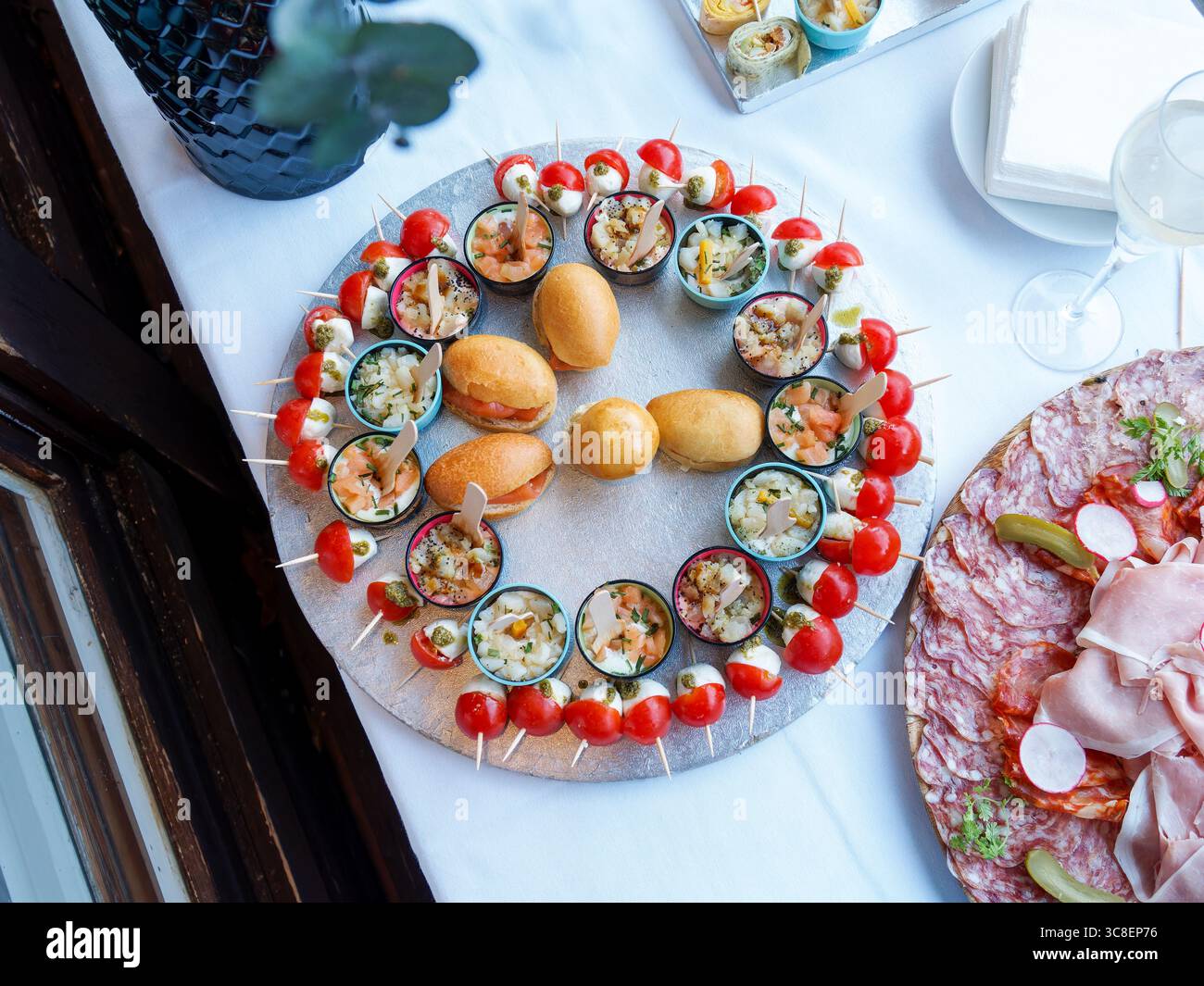 Vorspeisenplatte mit Mini-Burgern, Verrines, Tomaten-Mozzarella-Spießen und Aufschnitt, elegant für Hochzeiten oder festliche Empfänge eingerichtet. Stockfoto