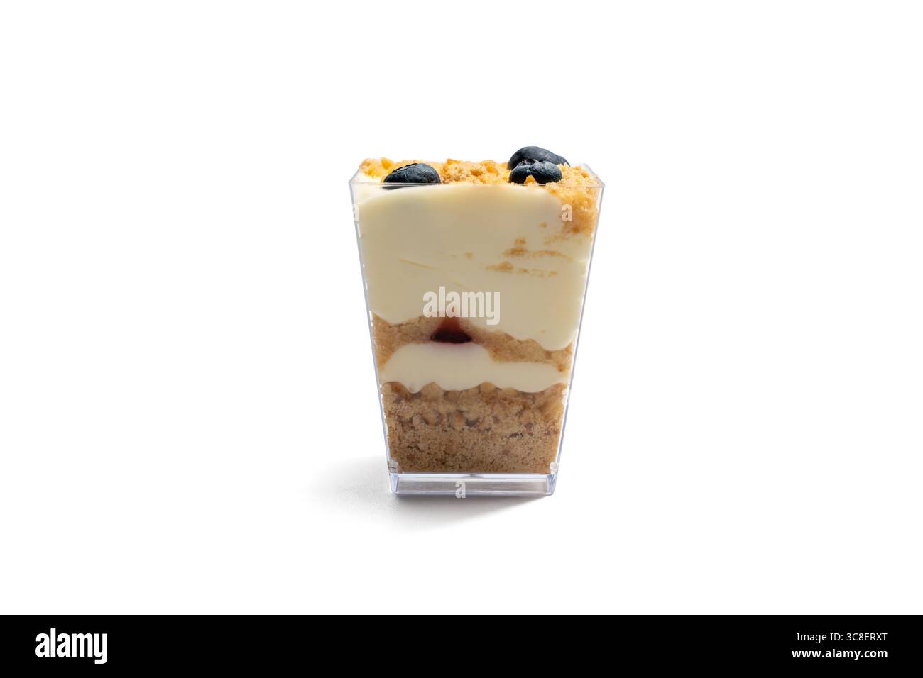 Mehrschichtiges Dessert in einer Tasse isoliert auf weiß. Ein Dessert in einer transparenten Tasse mit Schichten Sahne, Streusel und Beeren. Dieses stilvolle Dessert ist isoliert Stockfoto