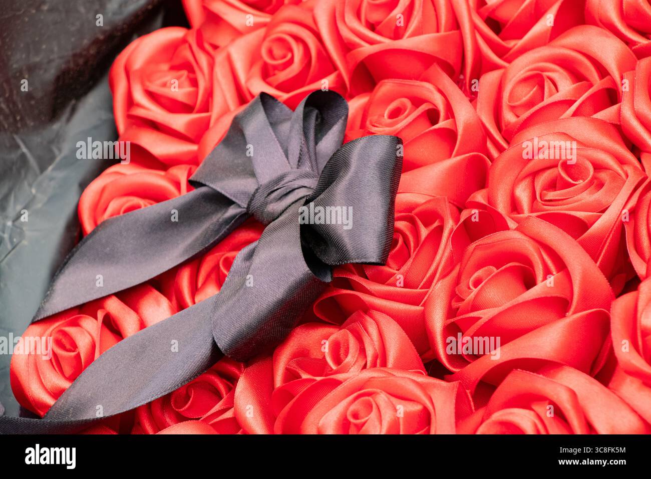 Ein Trauerstrauß aus roten Rosen mit schwarzem Bogen liegt als Opfergabe auf der Gasse der Erinnerung, ein Symbol der Trauer, der Erinnerung und des Respekts für die gefallenen Helden Stockfoto