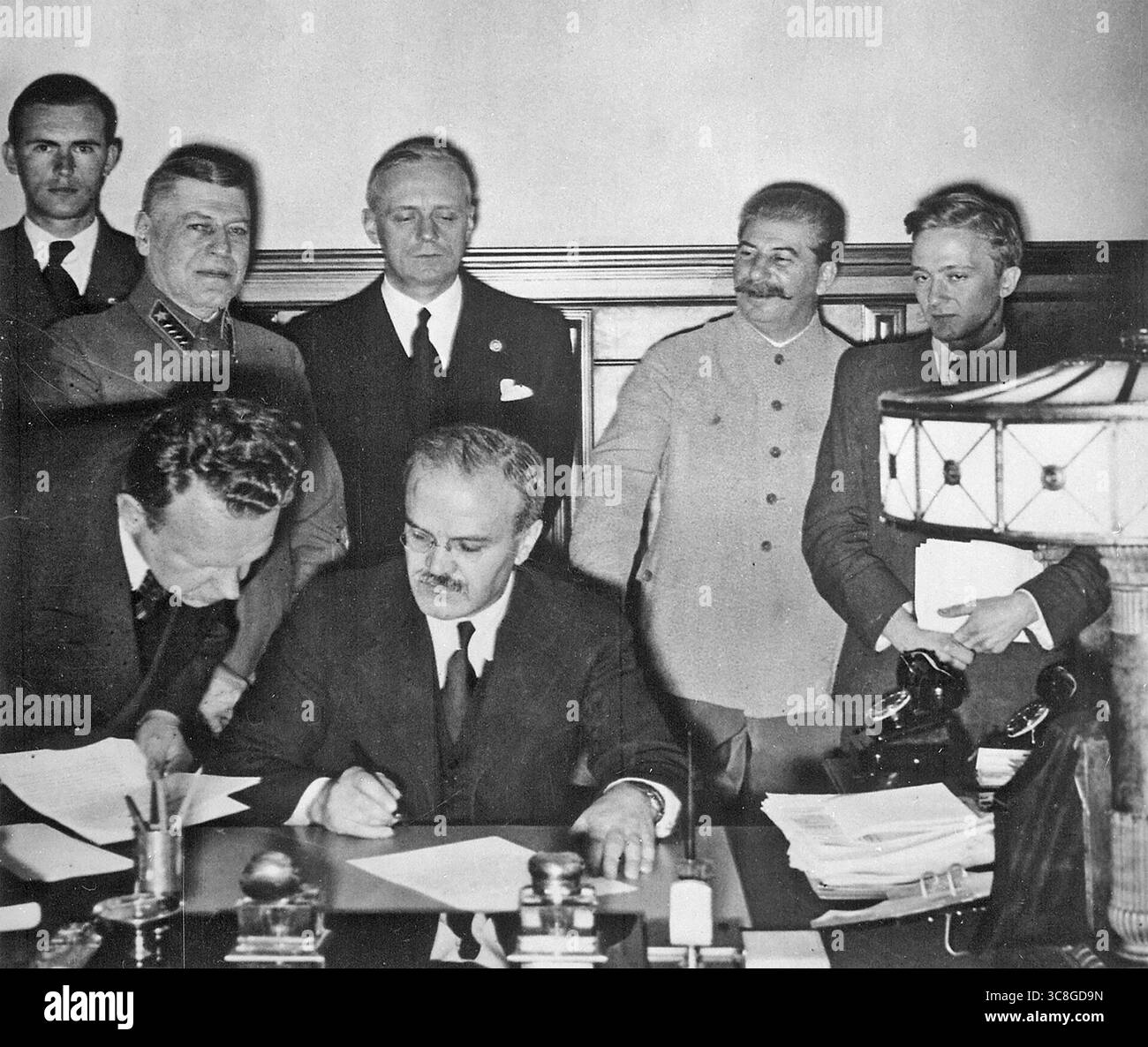 PAKT MOLOTOW-RIBBENTROP 23. AUGUST 1939. Ein Berater hilft Molotow, seine Unterschrift zur Ratifizierung des sowjetisch-deutschen nichtangriffssvertrags hinzuzufügen, den Stalin als zweiter von rechts neben Ribbentrop und Keitel ganz links beobachtet. Stockfoto