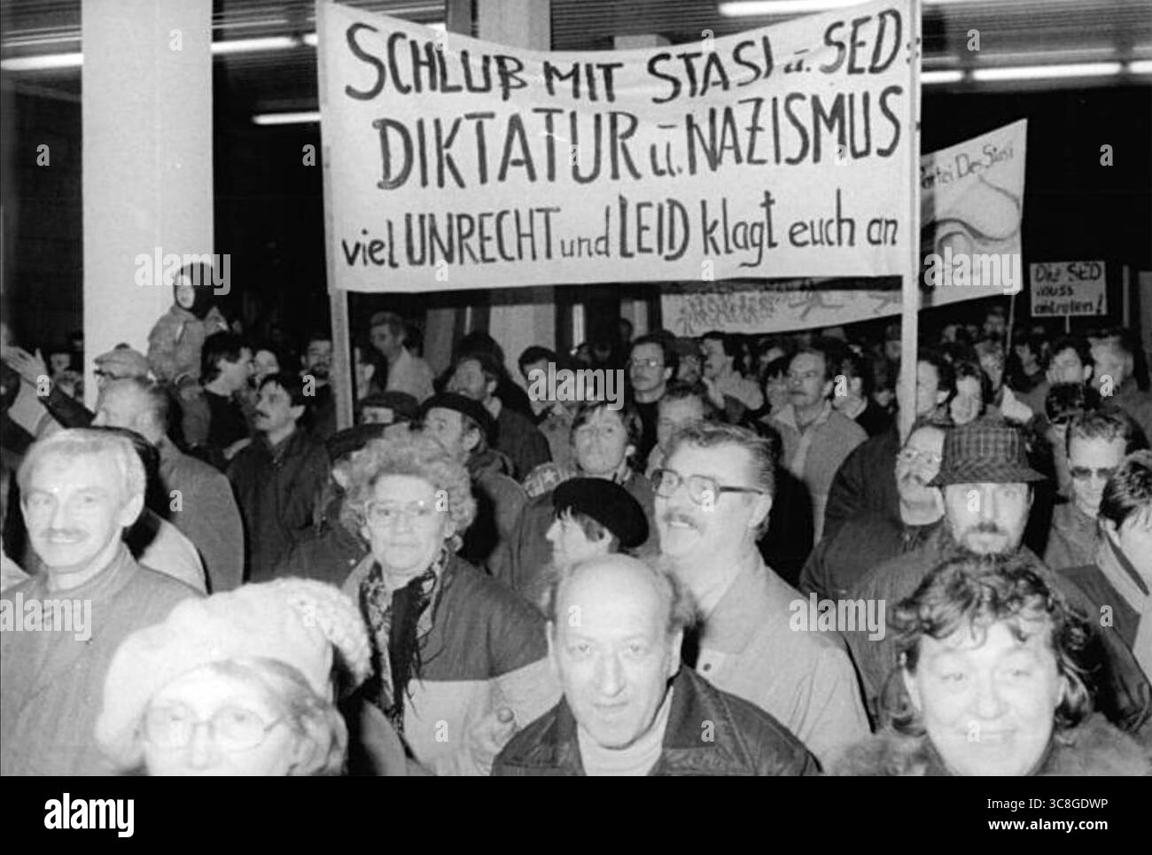 OSTDEUTSCHE STASI. Demonstranten, die im Januar 1990 in das Berliner Stasi-Hauptquartier einmarschieren. Das Banner wirft der Stasi und der SED vor, Nazi-ähnliche Diktatoren zu sein Stockfoto
