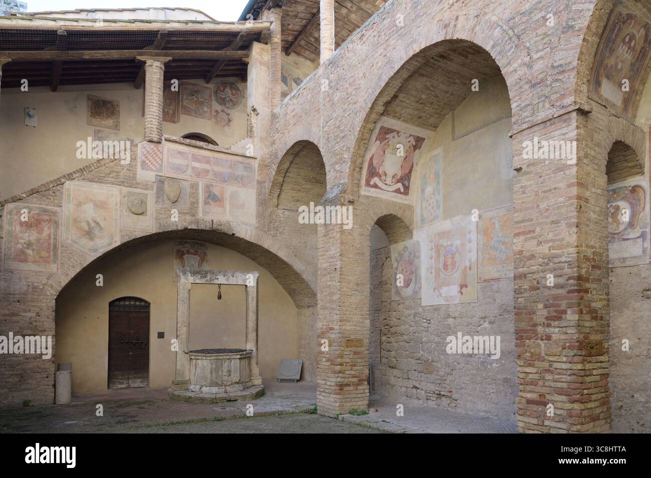 Innenhof mit Fresken und mittelalterlichen Wappen im Palazzo Comunale (Palazzo del Popolo), San Gimignano, Toskana, Italien. Stockfoto