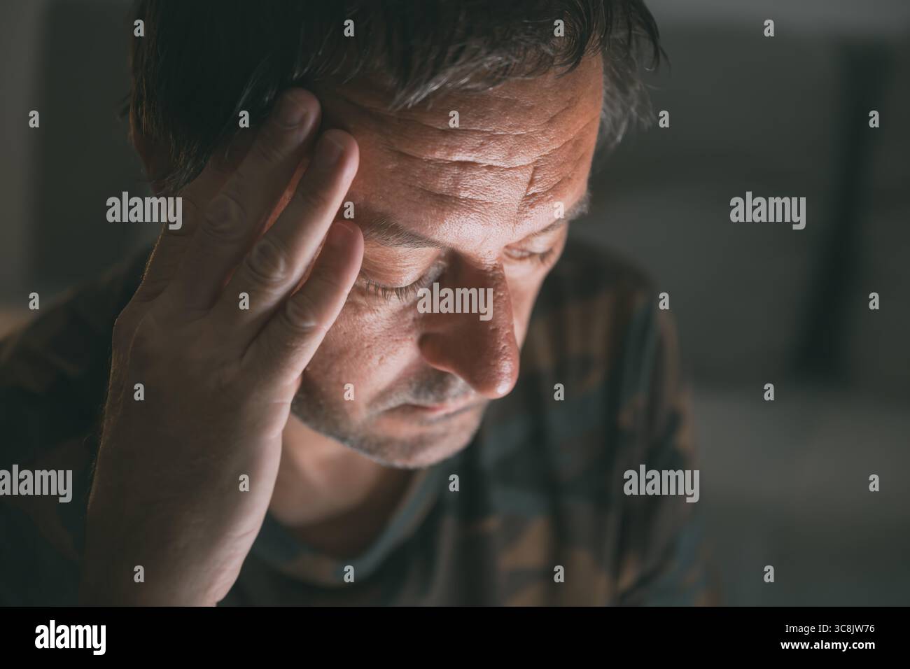 Reue und Bedauern, Porträt eines Mannes mittleren Alters im dunklen Raum, selektiver Fokus Stockfoto