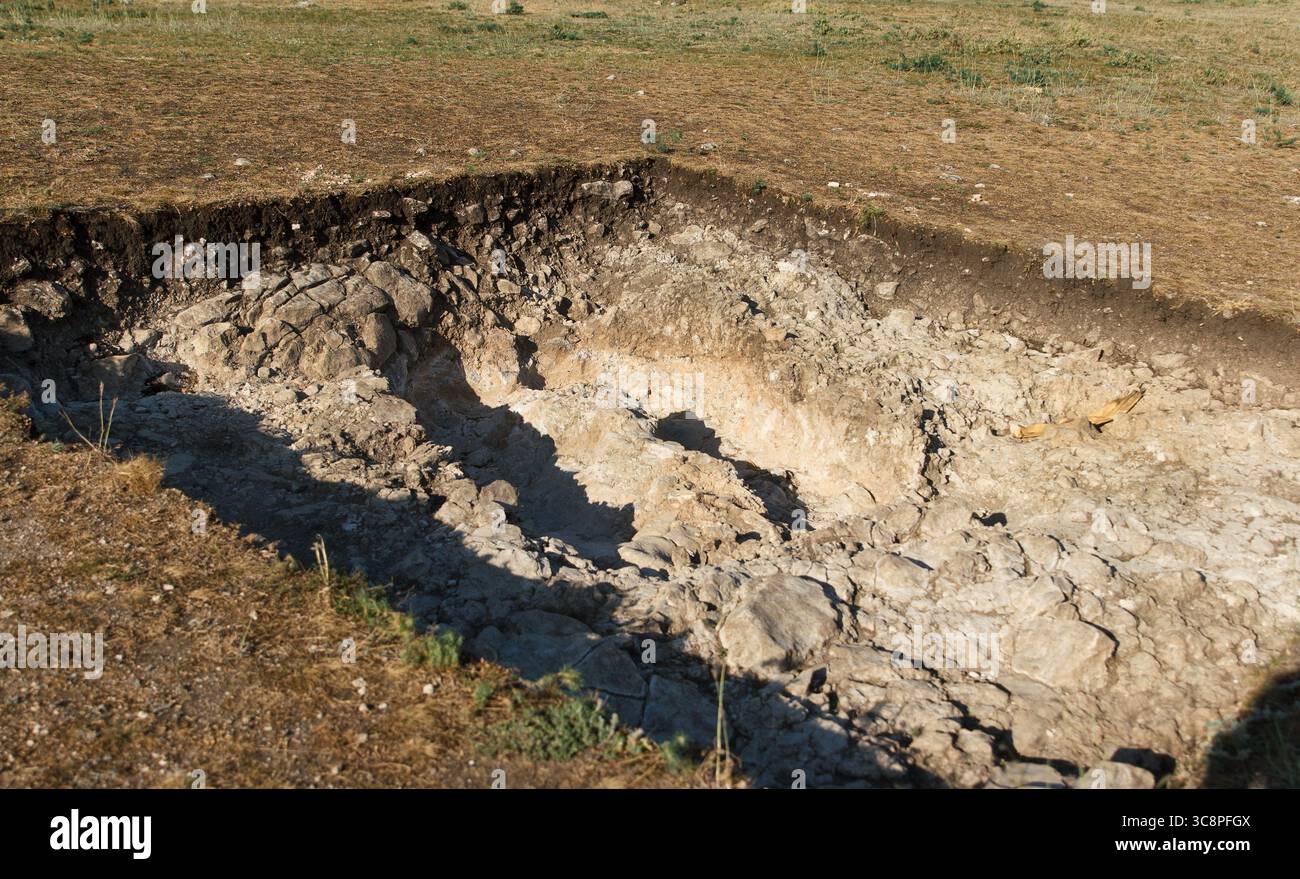 Freiliegende magische archäologische Grabstätte mit Bodenschichten und kalkhaltiger Oberfläche, Tageslichtfoto, natürliches Gelände, Konzept der Ausgrabung aus der antiken Geschichte Stockfoto