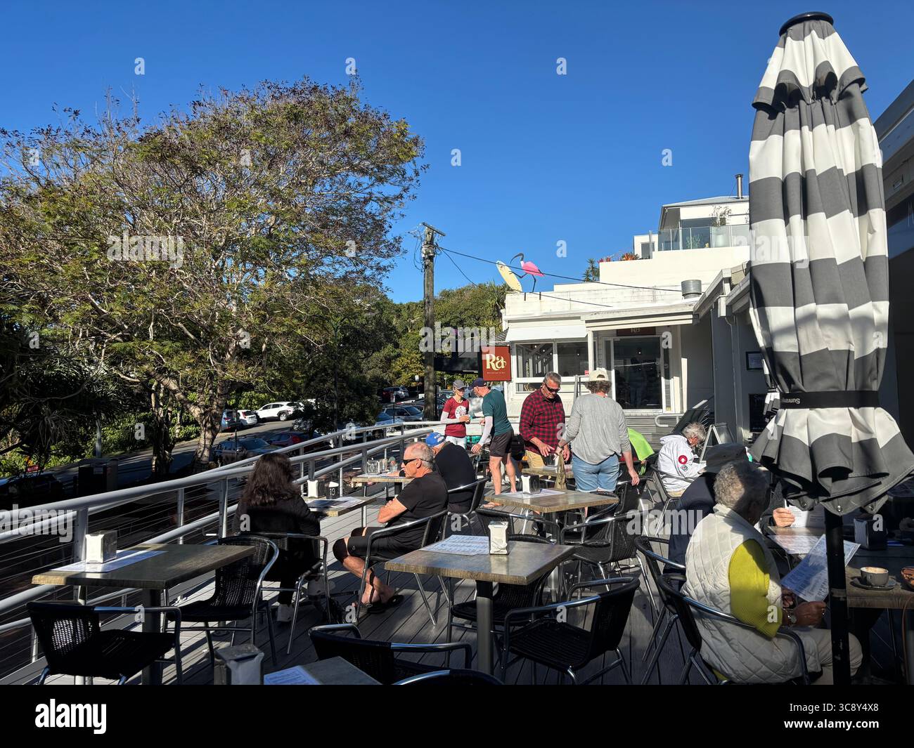 Leute sitzen an einem Wintermorgen im Café an Tischen im Freien, Sunshine Beach, Queensland, Australien. Kein MR oder PR Stockfoto