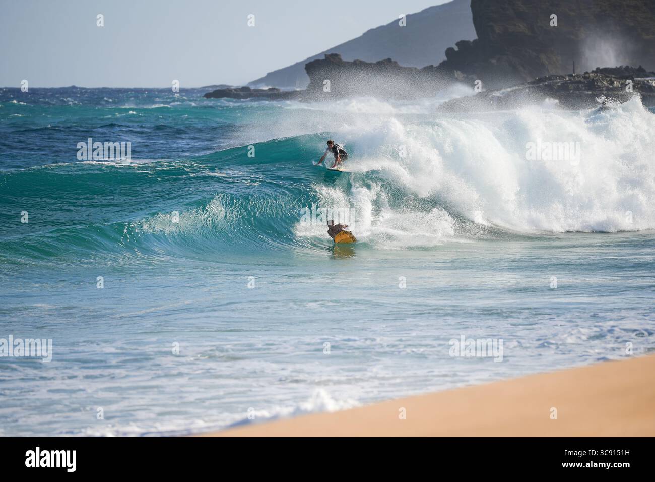 Bodyboarder reitet in einem gewaltigen Sturmschwall, der sich mit Kraft und Präzision vor dem Hintergrund des turbulenten Ozeanhimmels durch schäumende Wellen zieht. Honolulu HI Stockfoto