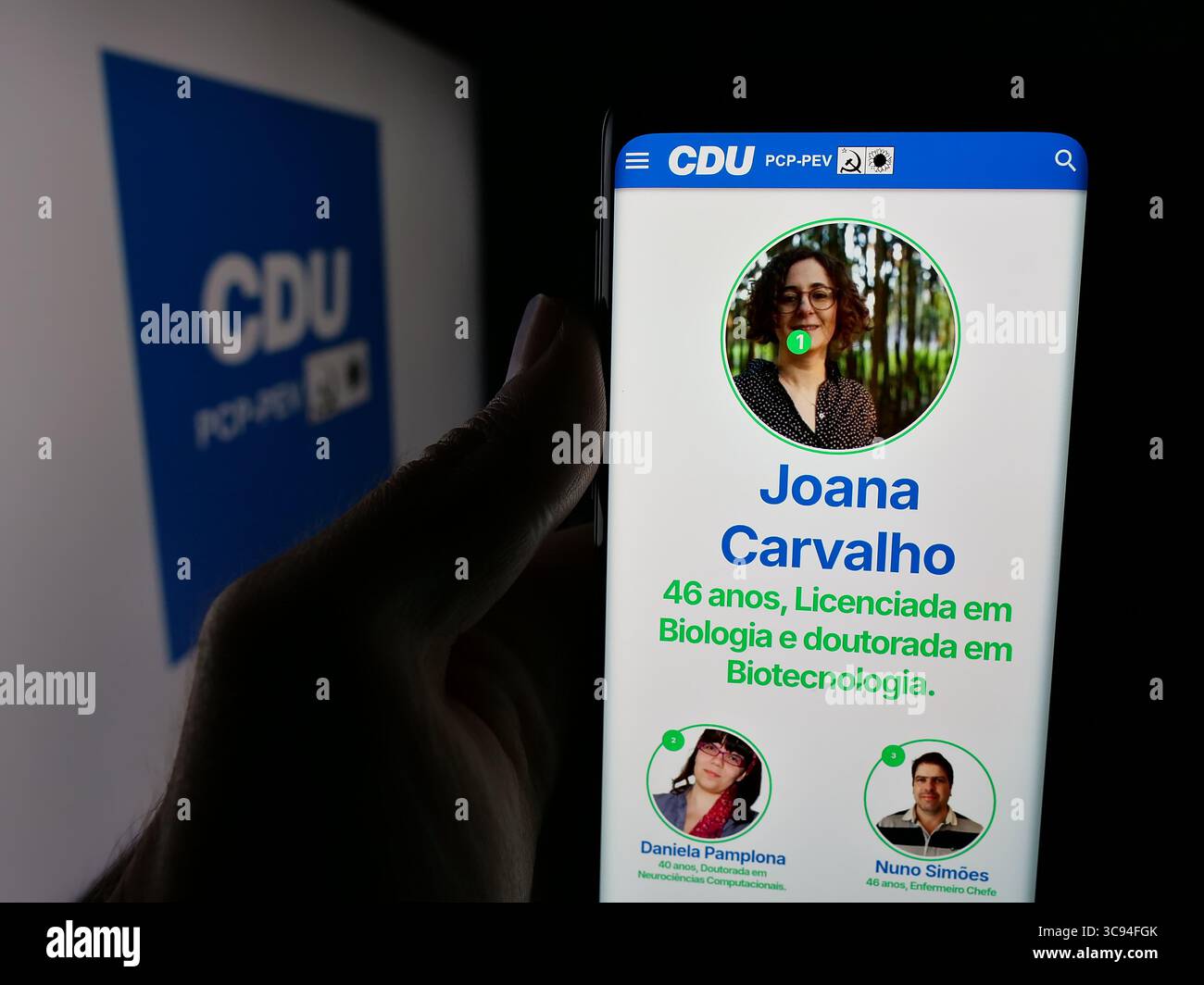 In dieser Fotoabbildung hält eine Person ein Handy mit der Webseite von Coligacao Democratica Unitaria (CDU PCP-PEV) vor dem Logo. Stockfoto