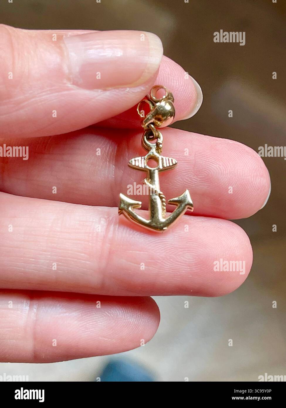 Hand hält einen ankerförmigen Ohrring. Ansicht schließen. Stockfoto
