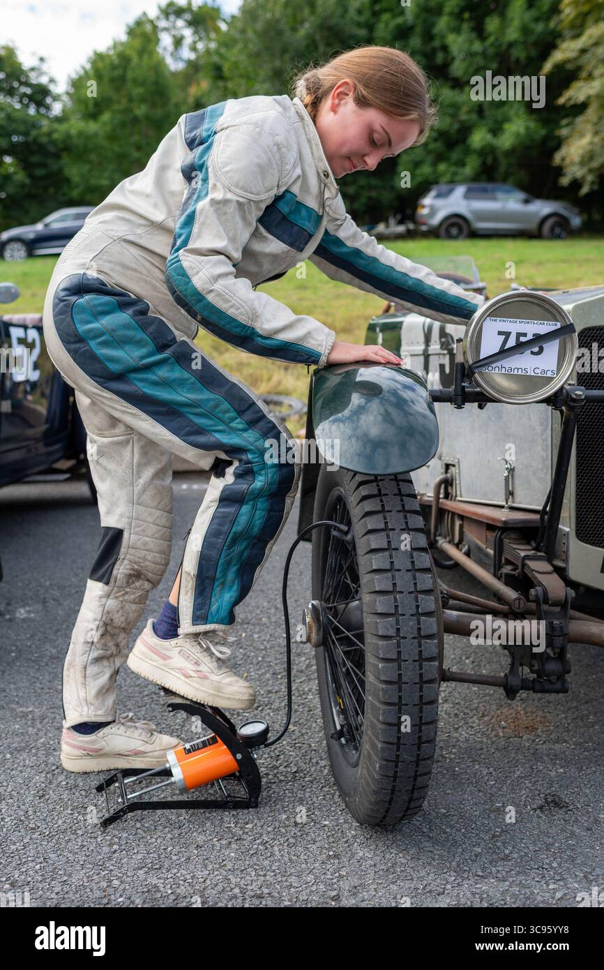 Die junge Fahrerin pumpt den Vorderreifen in Vorbereitung auf den historischen Aufstieg des VSCC Prescott. Stockfoto