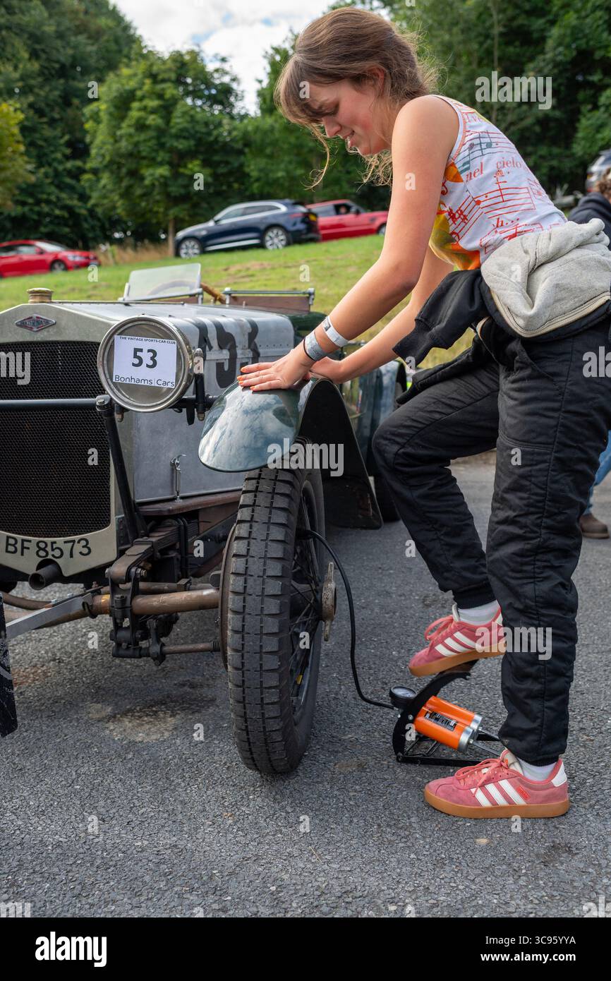 Die junge Fahrerin pumpt den Vorderreifen in Vorbereitung auf den historischen Aufstieg des VSCC Prescott. Stockfoto