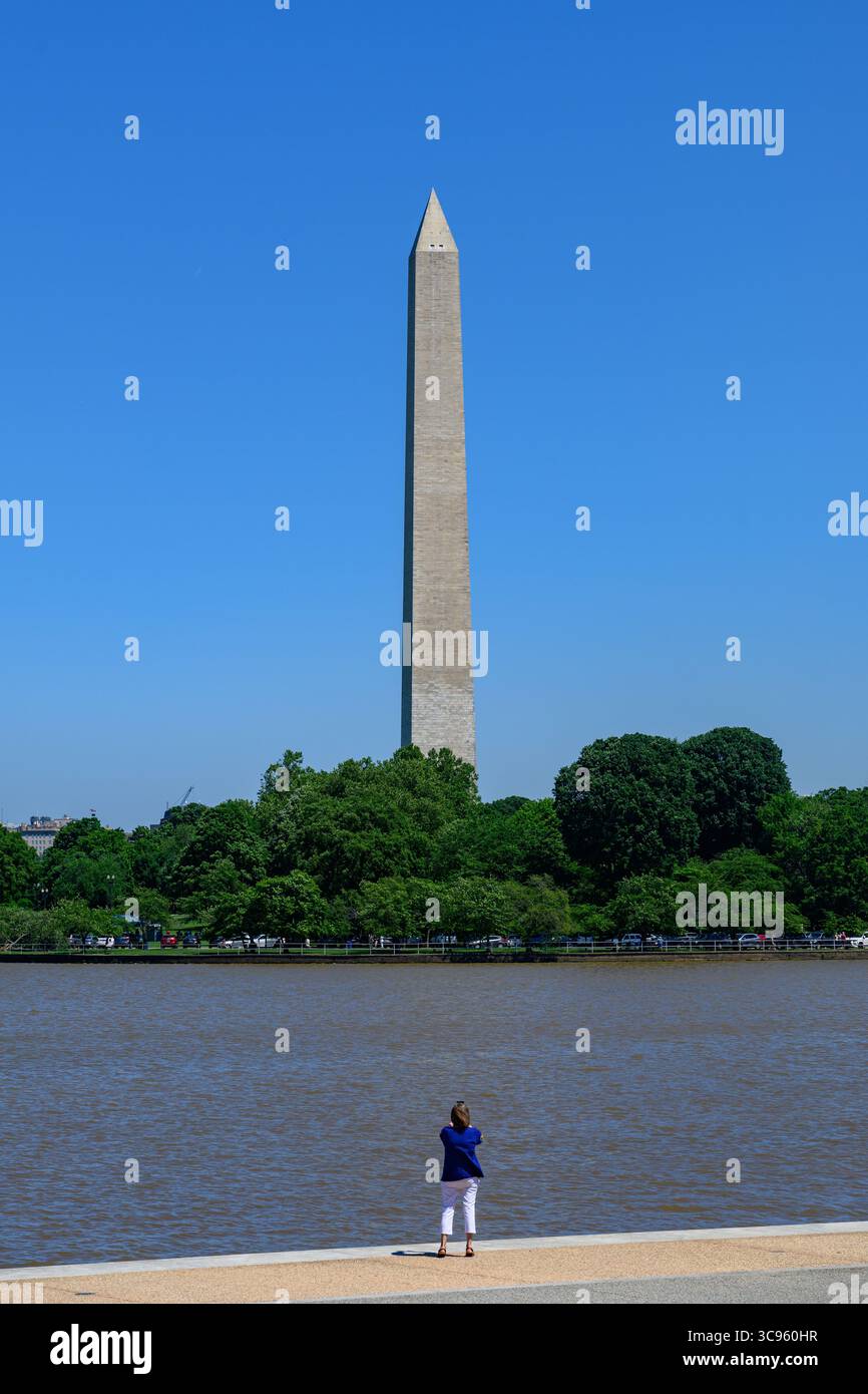 Eine Dame fotografiert das Washington Monument, das höchste Steinbauwerk der Welt, gegenüber dem Tidal Basin, Washington DC, USA. Stockfoto