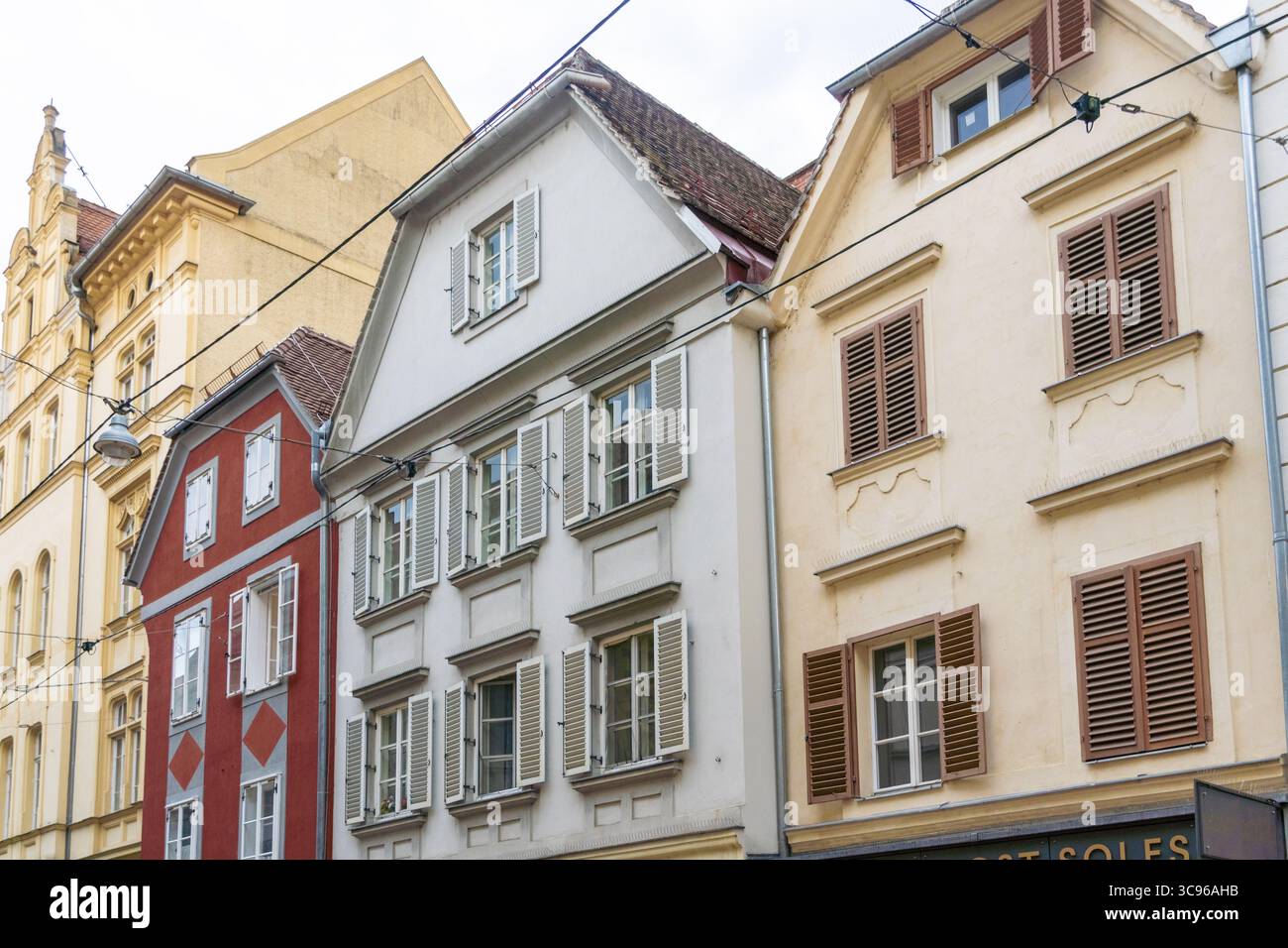 Blick auf lebendige Gebäude nebeneinander, mit einzigartigen architektonischen Stilen und Farben unter einem bewölkten Himmel, die eine fesselnde Straßenszene schaffen, Graz, Steiermark, Österreich. Stockfoto