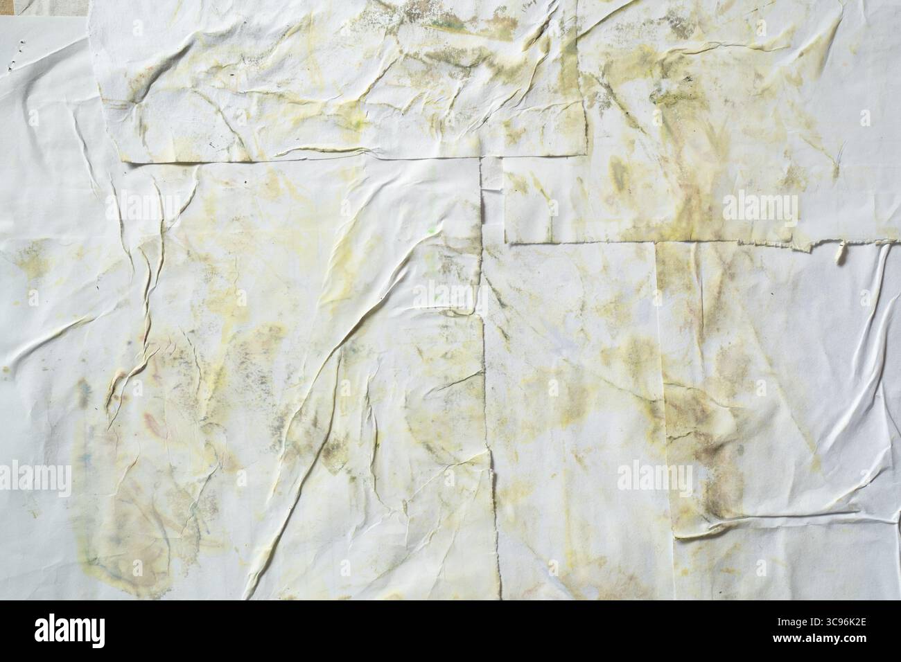 Schmutzige weiße Poster-Textur auf der Wand mit gelbem Fleck Stockfoto