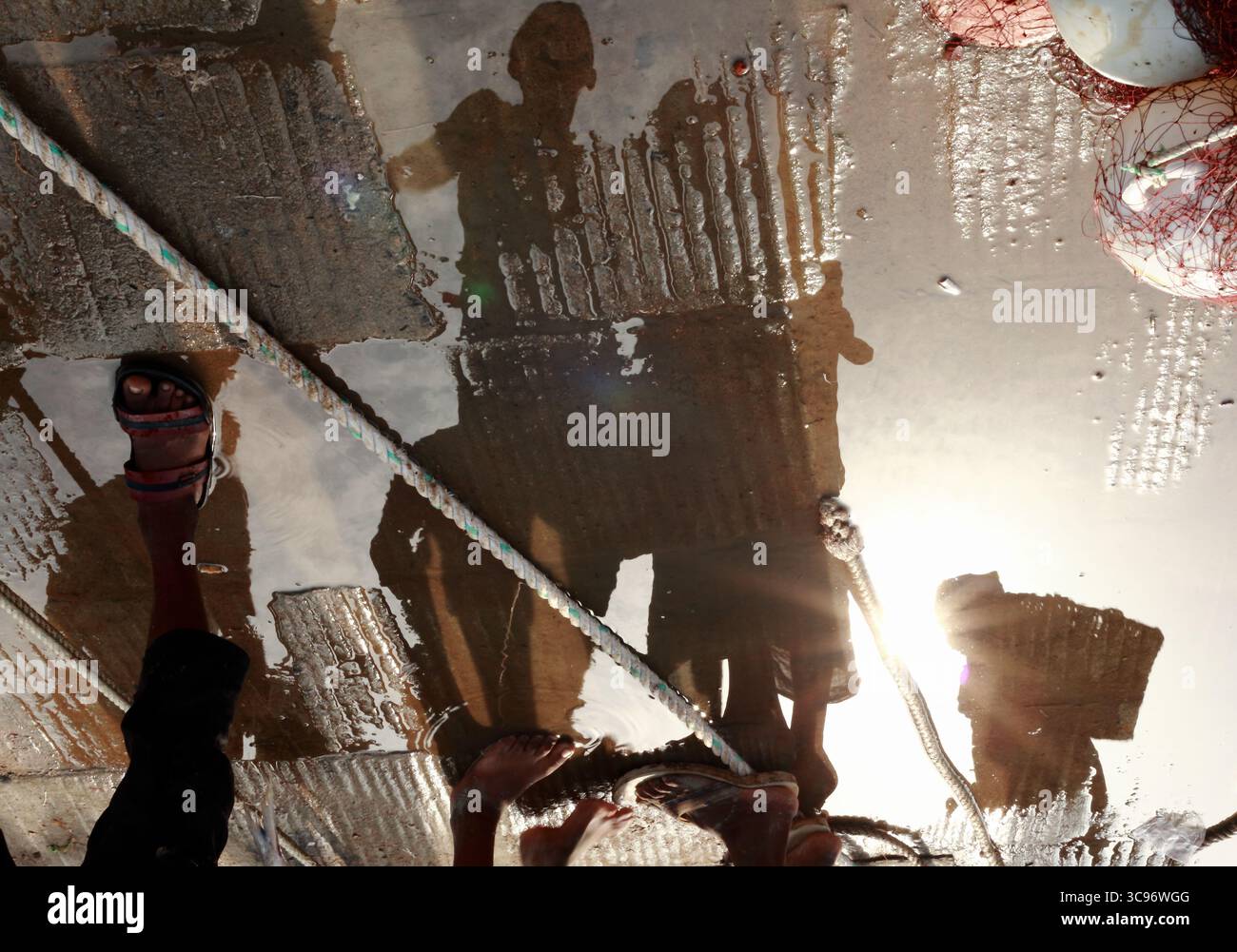 Ichanagar, Bangladesch - 03. August 2018: Blick auf Figuren, die sich im Wasser spiegeln, in Licht und Schatten schimmern und die Szene darüber mit markanter Klarheit und gestreuten Goldtönen spiegeln. Stockfoto