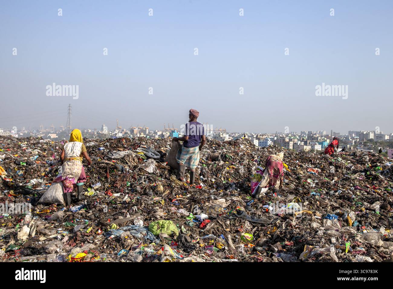 Chittagong, Bangladesch - 08. März 2024: Blick auf Figuren inmitten der weitläufigen Deponie, die sich in starkem Kontrast zur Skyline der Stadt in der Ferne befinden. Stockfoto