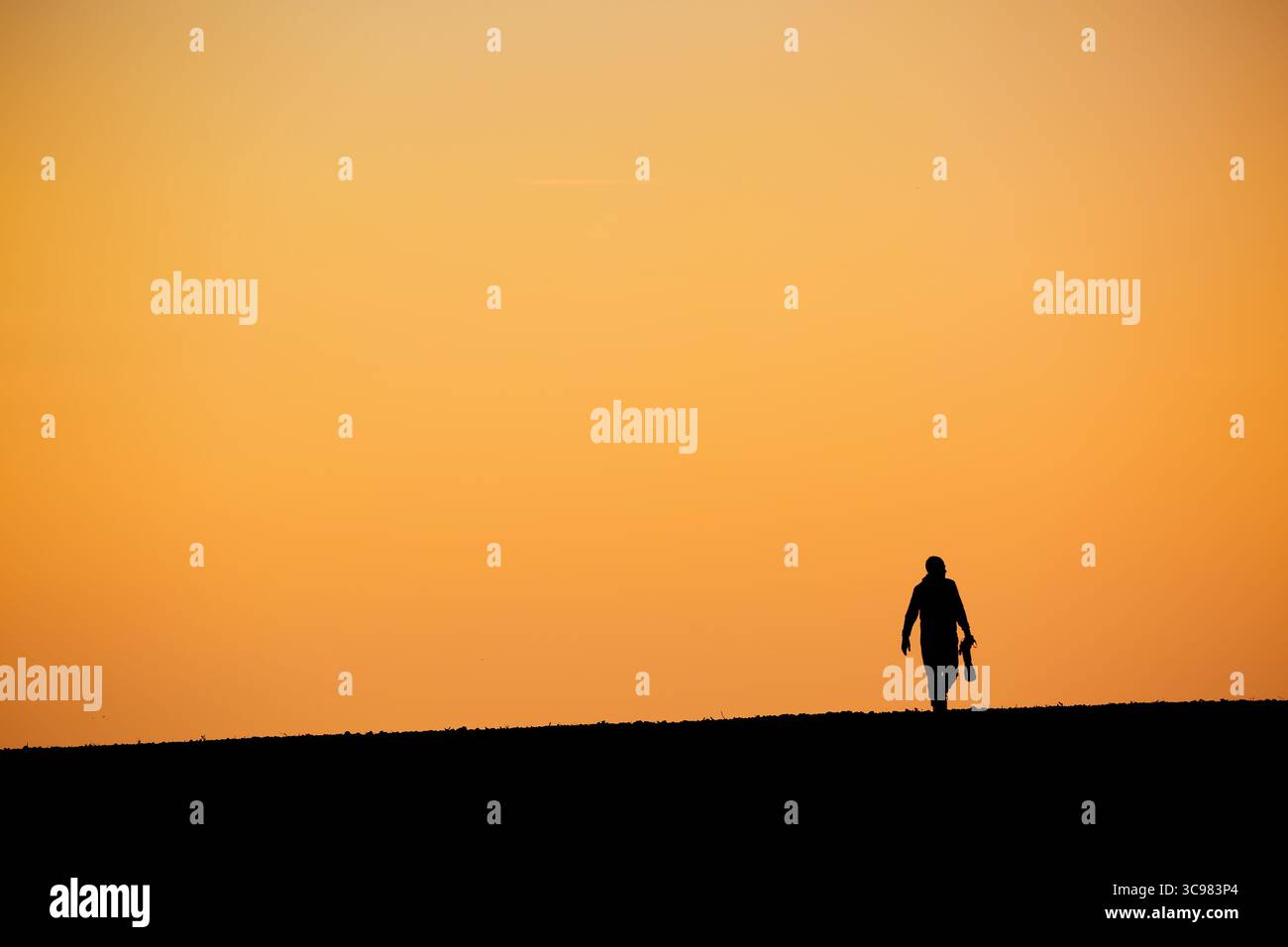 Silhouette Mann mit großem Teleobjektiv vor orangem Hintergrund des Sonnenuntergangs Stockfoto