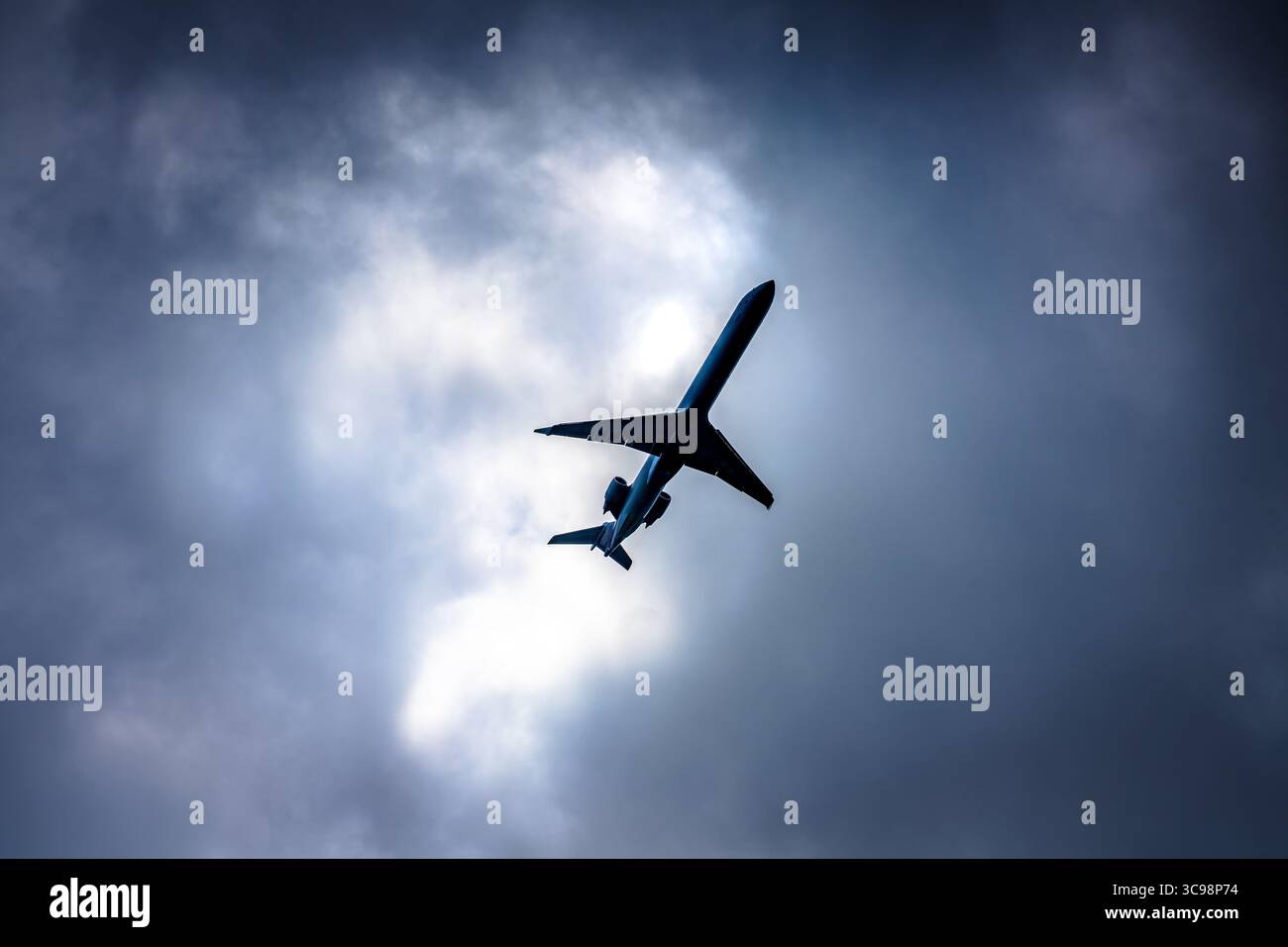 Flugzeug im Flug auf bewölktem Tagesblick von unten, Luftverkehr Stockfoto