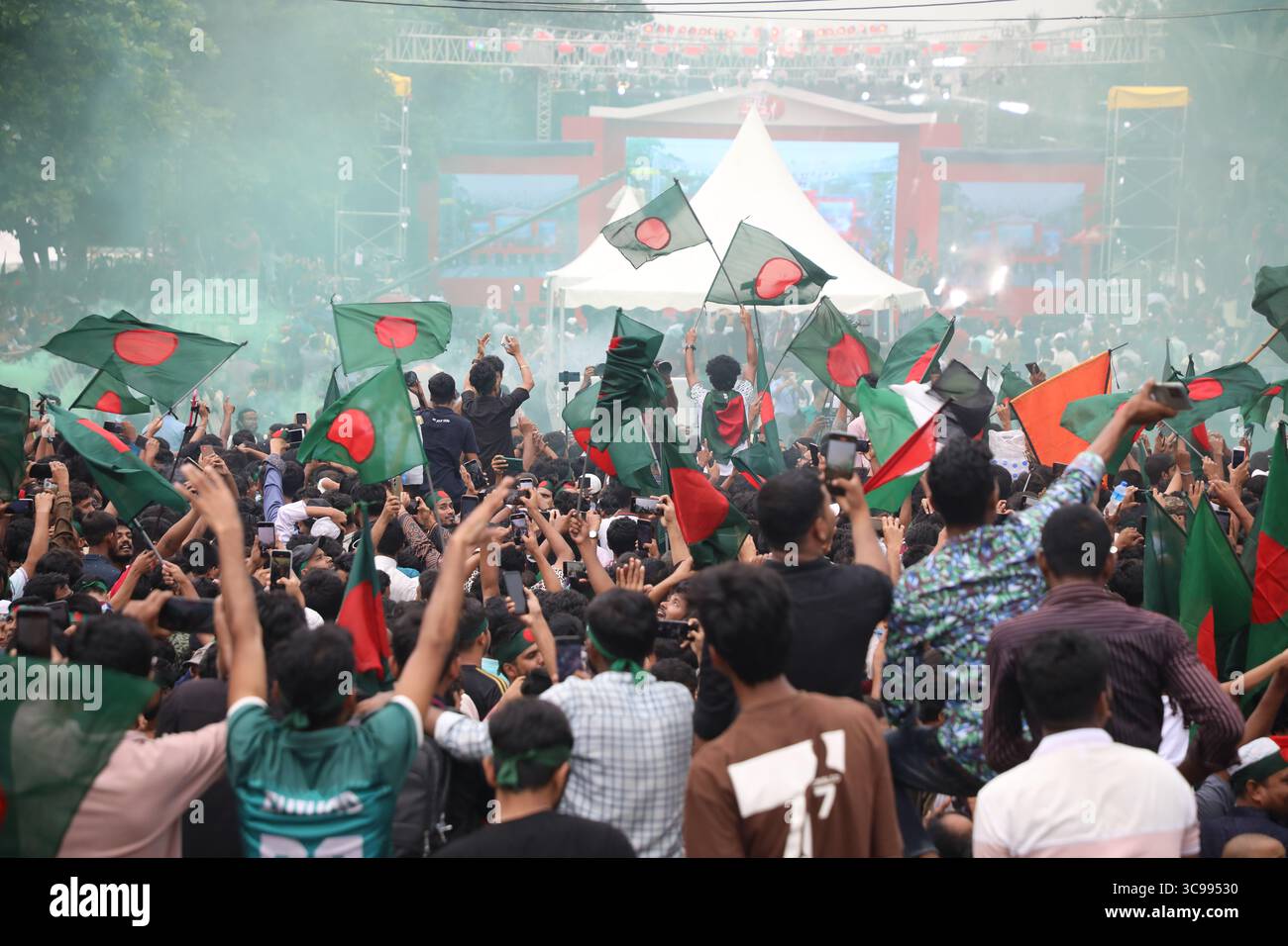 Menschen halten Bangladeschs Nationalflagge, während sie am 5. August 2025 während des „Juli-Aufstands“ in Dhaka, Bangladesch, feiern. Bangladeschs Interimsführer am 5. August feierte den einjährigen Jahrestag seit dem Sturz des autokratischen Regimes von Scheich Hasina, indem er die Menschen aufforderte, die "Chance" der Reform zu ergreifen. Stockfoto