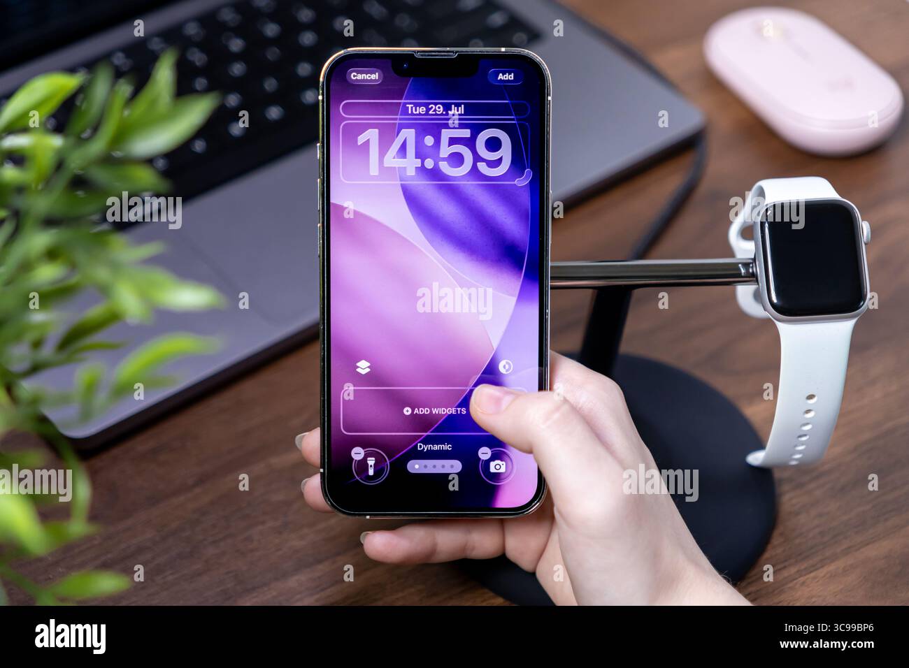 Poznan, Polen – 29. Juli 2025: Hand passt das Apple iPhone mit der ios 26 Liquid Glass-Schnittstelle an und zeigt dynamische Bildschirmsperren, gepaart mit einem Stockfoto