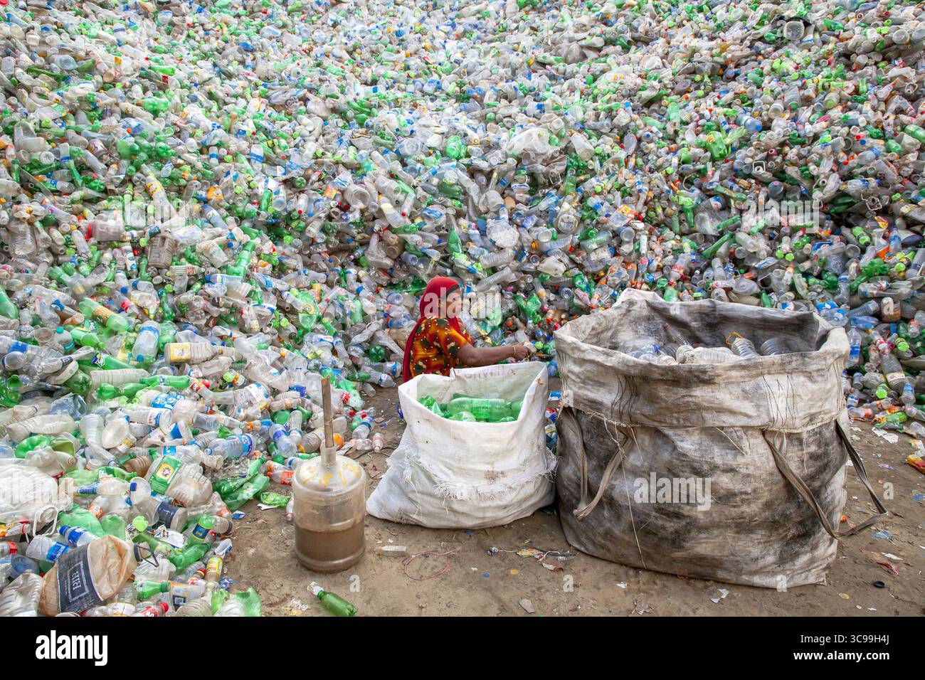 Chittagong, Bangladesch - 22. September 2022: Blick auf eine Frau inmitten eines Meeres von weggeworfenen Plastikflaschen, die den Abfall in einer lebhaften Darstellung der Umweltherausforderungen sortieren. Stockfoto