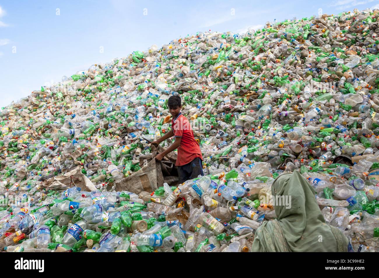 Chittagong, Bangladesch - 22. September 2022: Blick auf einen riesigen, hoch aufragenden Haufen von weggeworfenen Plastikflaschen, wo sich ein Junge inmitten der bunten Trümmer befindet. Stockfoto