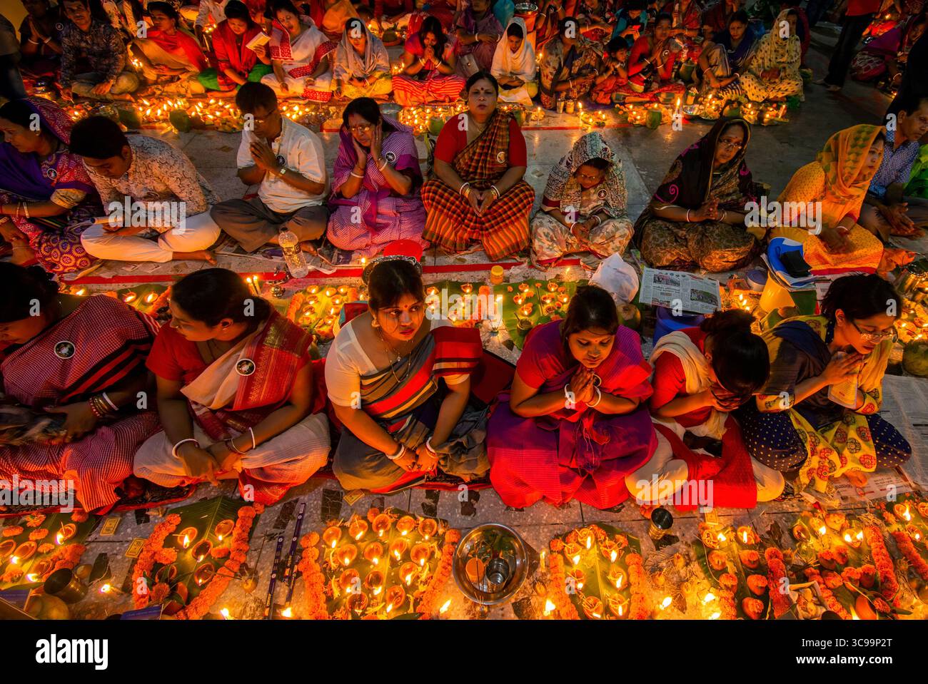 Dhaka, Bangladesch - 13. November 2018: Blick auf Gläubige, die im Gebet knieten, umgeben von dem warmen Schein zahlloser Diyas, die eine Szene der Ruhe schaffen Stockfoto