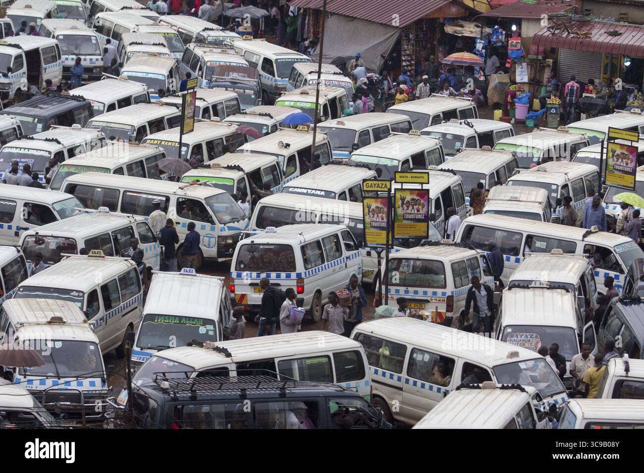Kampala, Uganda - 25. November 2014: Blick auf einen belebten Taxipark mit einem Meer von weißen Minibussen, die eng zusammengepackt sind und die pulsierende Energie der Stadt widerspiegeln. Stockfoto