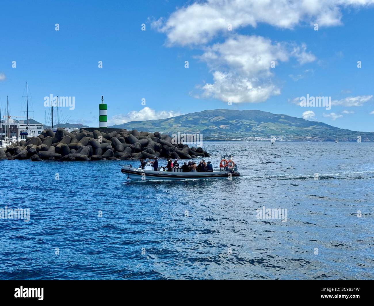 Touristen-Schnellboot Rückkehr zum Hafen von Ponta Delgada nach einem Tauchausflug, mit dem vulkanischen Berg Lagoa do Fogo im Hintergrund, São Miguel Isl - Smartphone-aufgenommenes Stockfoto