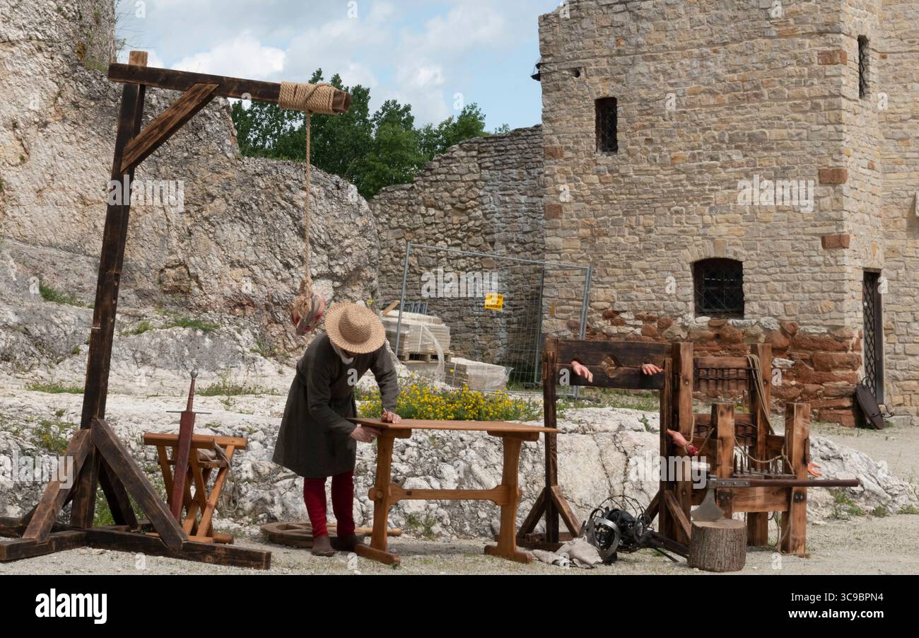 Person, die mittelalterliche Foltergeräte während der historischen Nachstellung an den Burgruinen demonstriert Stockfoto