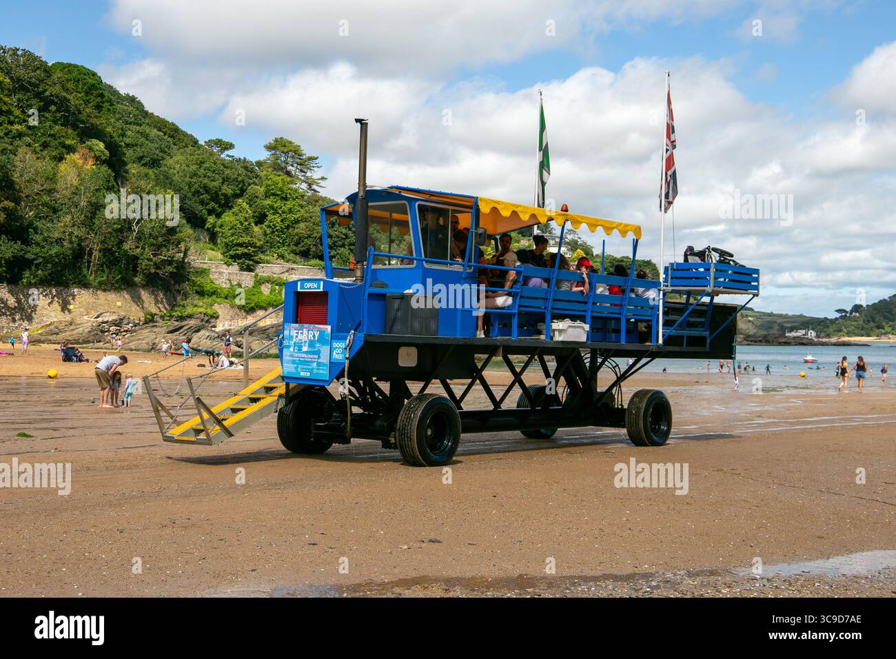 Ein blauer Seetraktor in South Sands, um Menschen über den Strand zu einer kleinen Fähre mit Menschen und üppiger grüner Landschaft zu transportieren Stockfoto