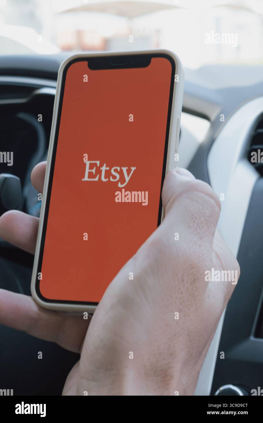 Rethymno, Griechenland. Juli 2025. Die Hand eines Mannes in einem Auto hält ein Telefon mit geöffneter Etsy-App Stockfoto
