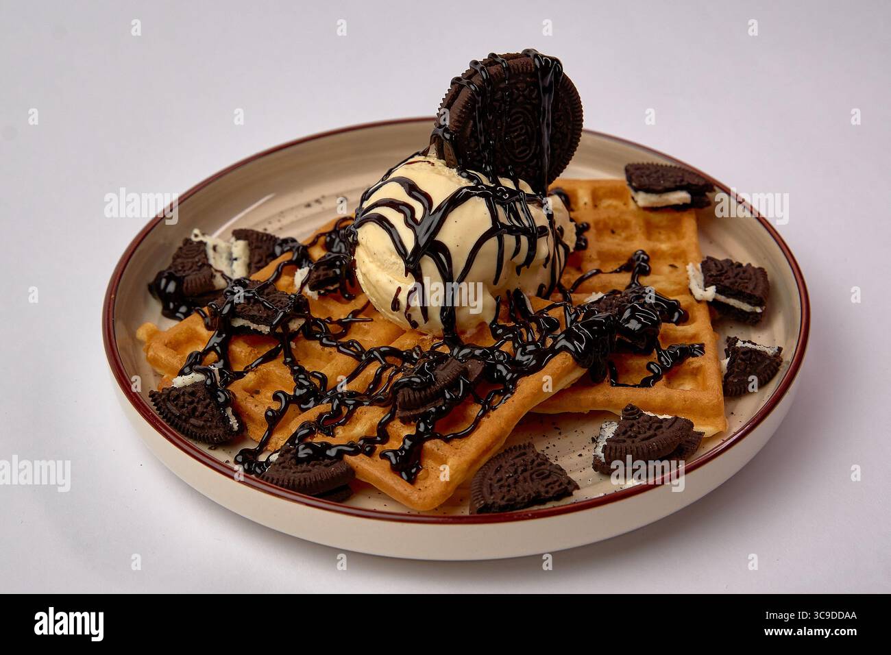 Köstliches Waffeldessert mit Eiscreme, Oreo-Cookies und reichhaltigem Schokoladensirup für eine verlockende Überraschung Stockfoto