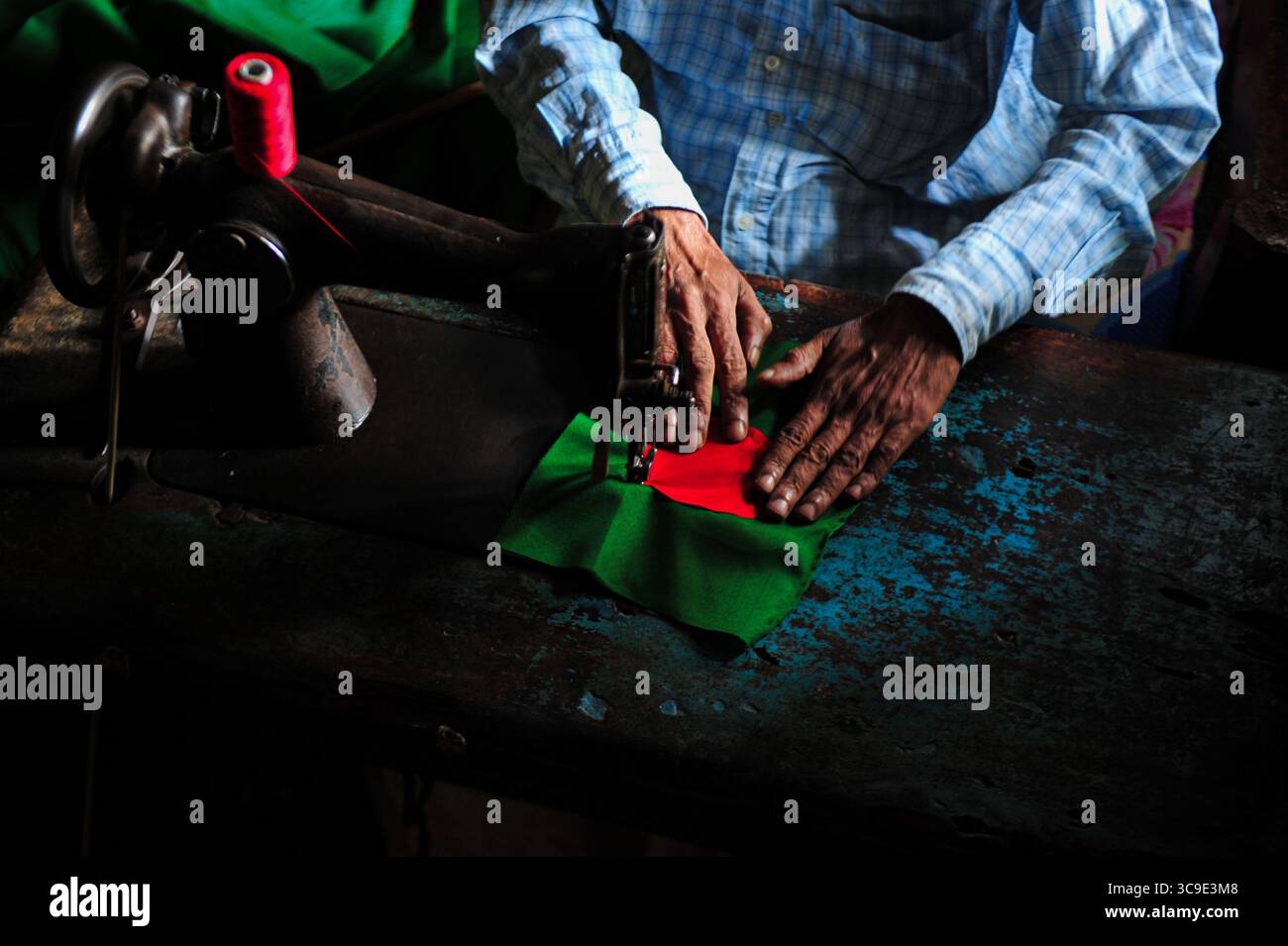 Dezember 2022: 12. Dezember 2022. Sylhet-Bangladesch: Ein 55-jähriger Schneider Kaosar Khan aus Sylhets Loharpara, der die Nationalflagge von Bangladesch näht. Etwa die Hälfte der Tausenden von Nationalflaggen, die er das ganze Jahr über näht, wird im Dezember verkauft. Bangladesch erzielte im Dezember 1971 vor 51 Jahren den Sieg im bewaffneten Befreiungskrieg . Im Austausch für 3 Millionen Leben und Ehre von 200.000 Frauen in neun Monaten Krieg kam dieser Moment am 16. Dezember. Bangladesch feiert diese Leistung noch immer mit gebührender würde. (Bild: © MD Rafayat Haque Khan/ZUMA Press Wire) Stockfoto