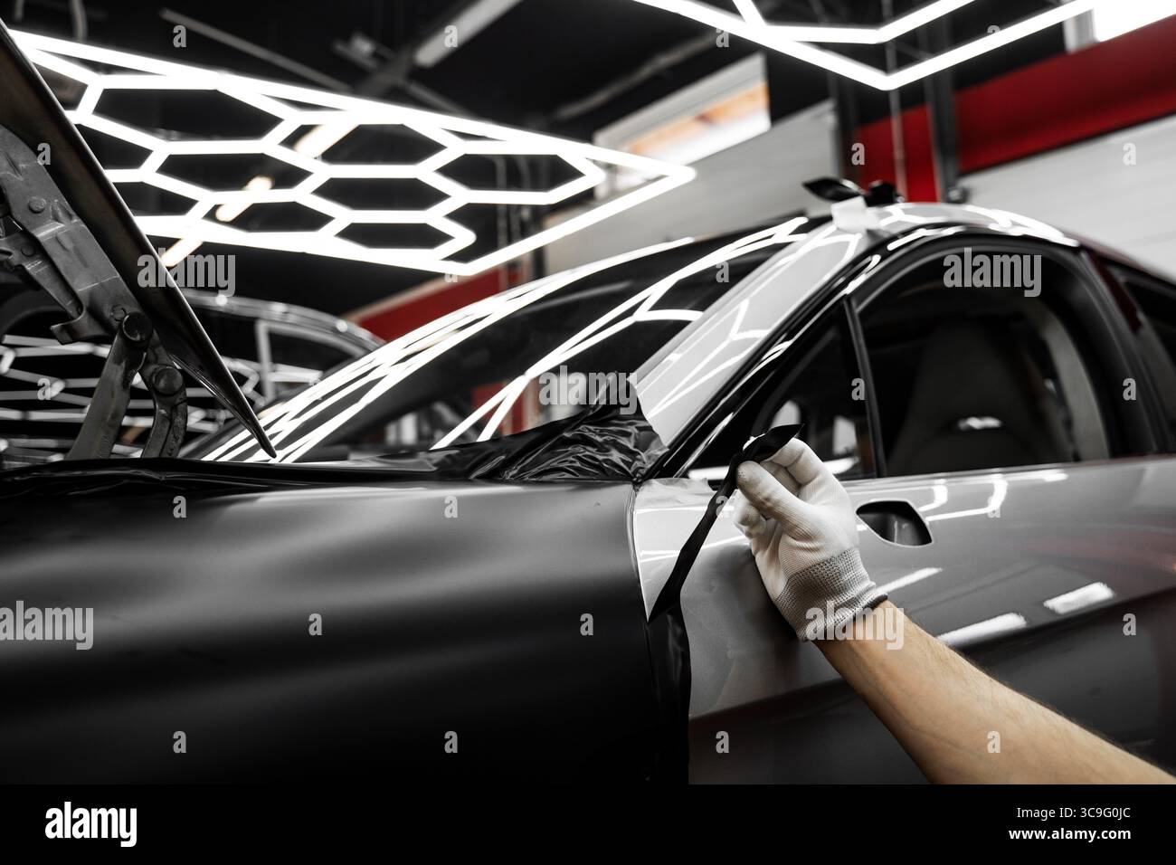 Vinyl-Verpackung Für Autos Mit Vollpaneel. Die großformatige Vinylfolie verwandelt das Außenmaterial des Fahrzeugs mit mattschwarzer Folie. Änderungen an der Anwendung der Autoverpackung Stockfoto