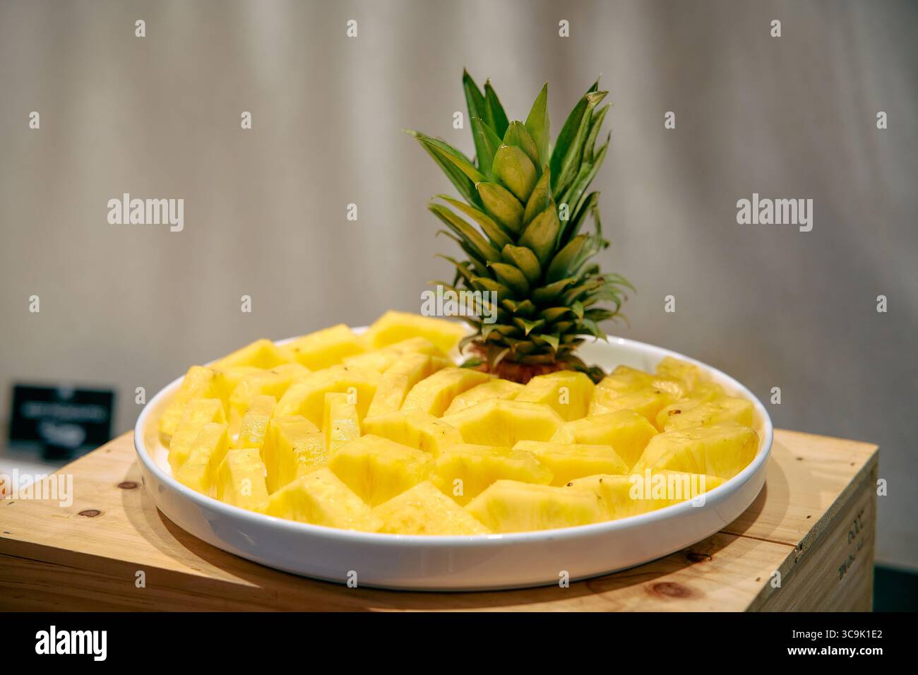 Eine frisch geschnittene Ananas auf einem weißen Teller mit saftig gelben Fruchtstücken zum Genuss Stockfoto