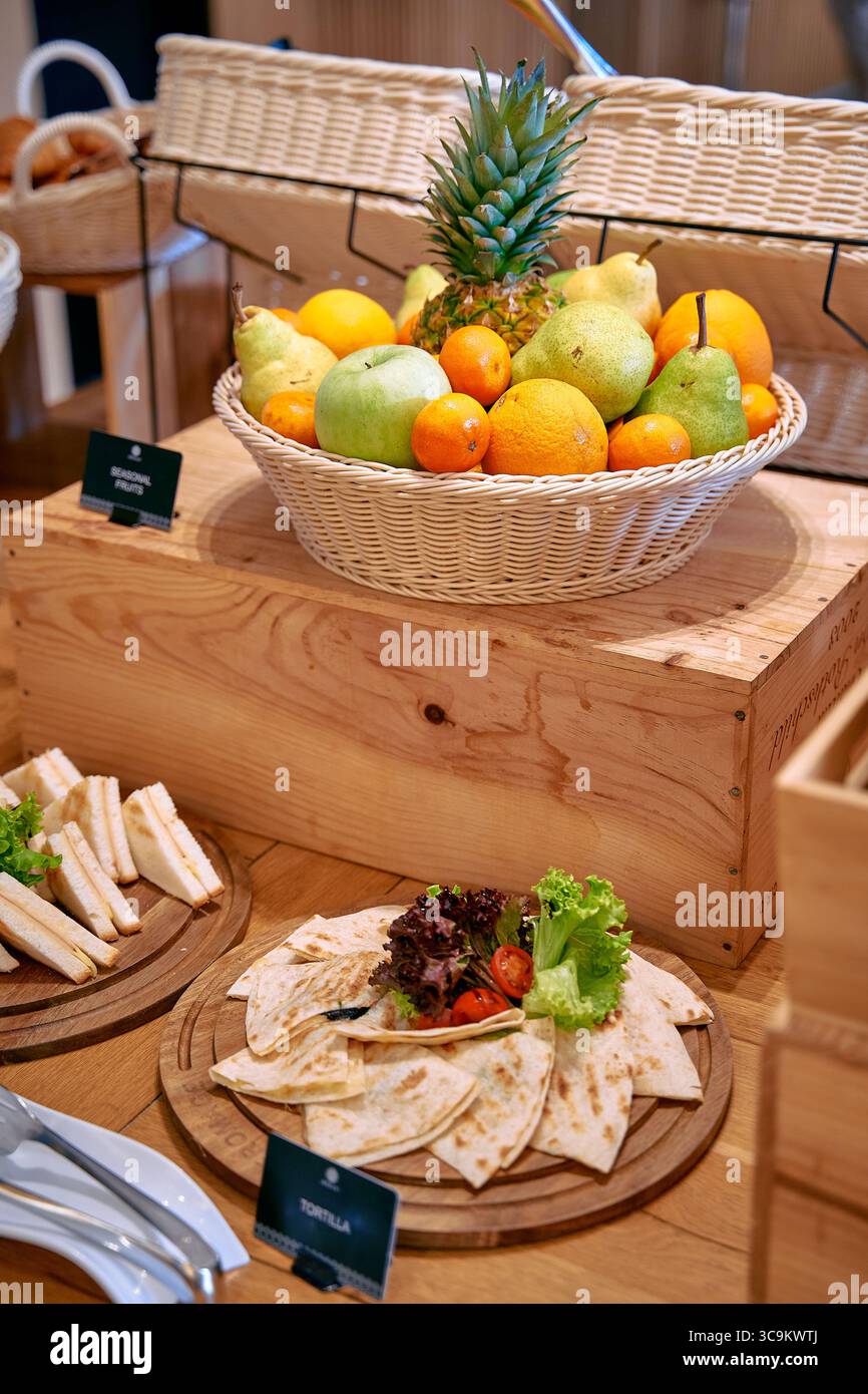 Eine lebhafte Auswahl an frischem Obst und Gemüse, elegant in einem gewebten Korb präsentiert, ergänzt durch eine ordentlich angeordnete Platte mit Tortillas und Stockfoto